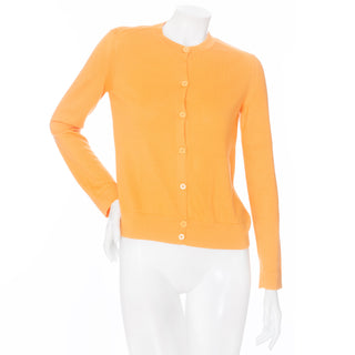 An orange cashmere button down long sleeve knit cardigan sweater by Hermes in a Size Small available at designer and vintage specialty consignment shop "Decades" in Los Angeles.