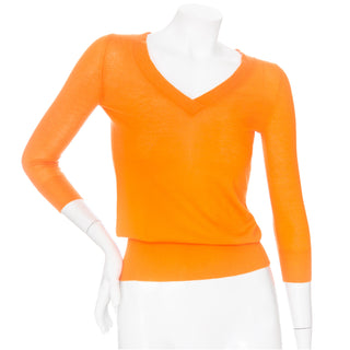 An orange cashmere v-neckline pullover by Hermes in an XS available at designer and vintage specialty consignment shop "Decades" in Los Angeles.