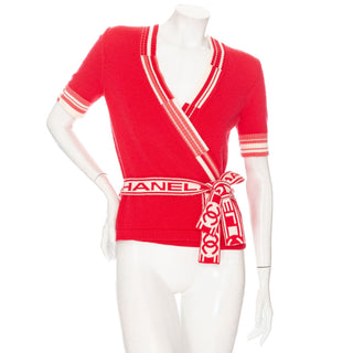 Preowned coral cashmere short sleeve cardigan wrap top with intarsia knit CC and logo self tie front. Size FR 34, an estimated US 2 or XS, and will fit a Size Small. In great preowned condition and available for purchase online and in store at Decades Los Angeles.